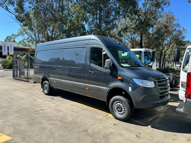 Gray van parked on a concrete surface with trees in the background